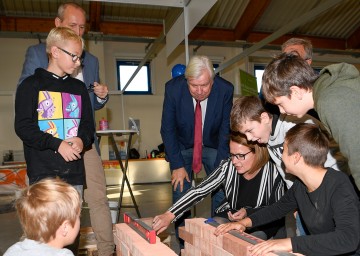 Bildungs-Landesrätin Christiane Teschl-Hofmeister, Bildungsdirektor Johann Heuras und Messedirektor Werner Roher mit Kindern beim Entwurf einer Ziegelmauer